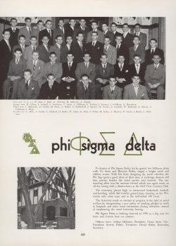 Phi Sigma Delta fraternity members seated for a group photo. The Phi Sigma Delta house is captured through leafless branches.