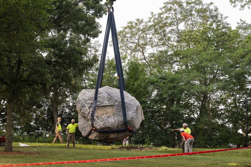 Chamberlain Rock being removed from campus grounds via crane by a construction crew.