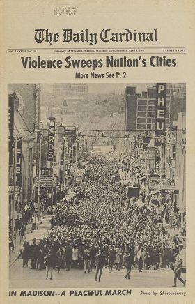 A Daily Cardinal newspaper frontpage with a large black and white photo of hundres of people marching on State Street following the killing of Dr. Martin Luther King Jr. and the headlines "Violence Sweeps Nation's Cities" and "In Madison -- A Peaceful March".