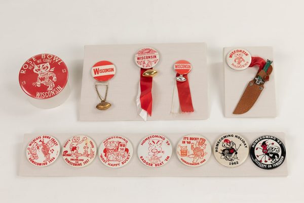 two rows of athletics memorabilia buttons, showing bucky badger and other slogans