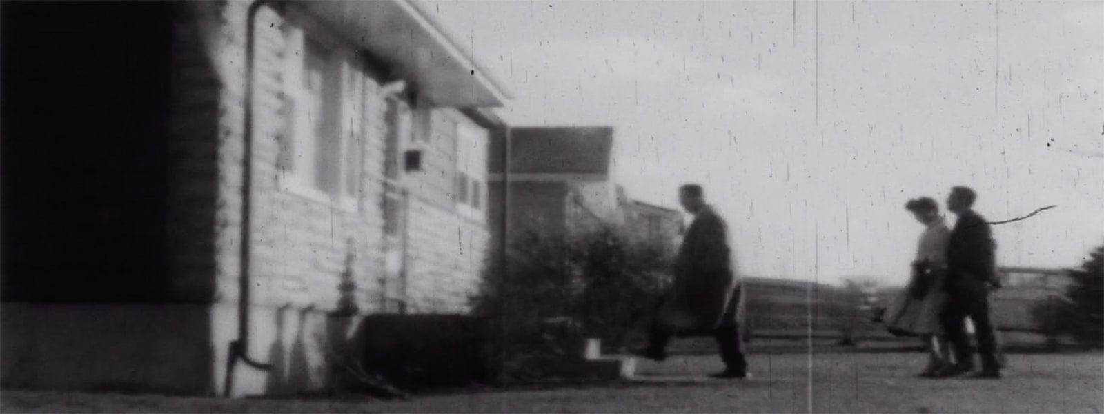 Still image of a man and a couple approaching a house for rent.
